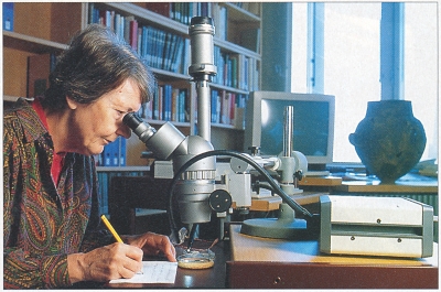 Foto von Margarita Primas, durch ein Mikroskop schauend bei der Arbeit